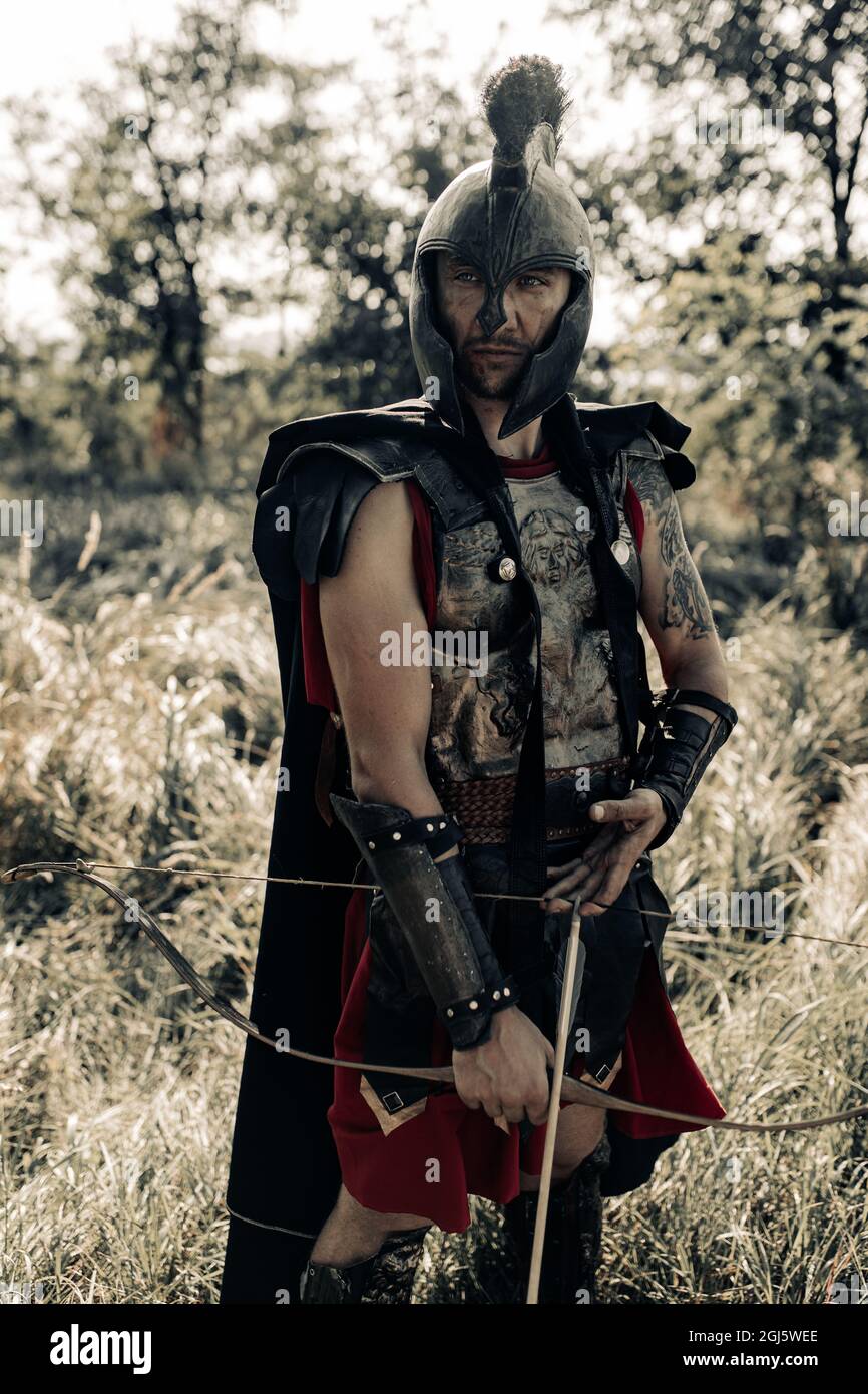 Ancient Spartan warrior archer in battle dress and black cloak stands among  meadow with bow and arrow in his hands Stock Photo - Alamy