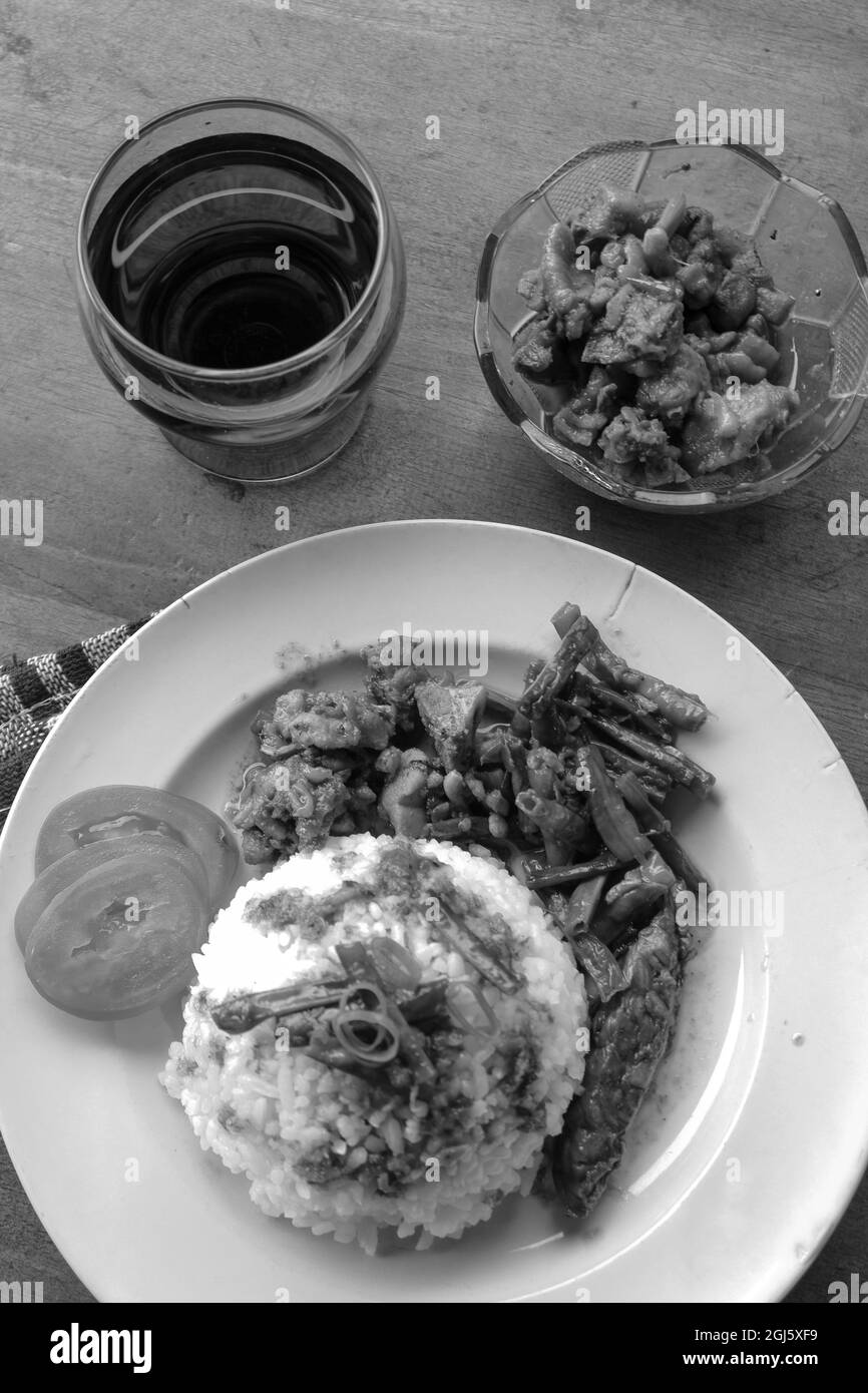 Vertical grayscale shot of a rice meal and side dishes, stew meat and beans vegetables Stock Photo