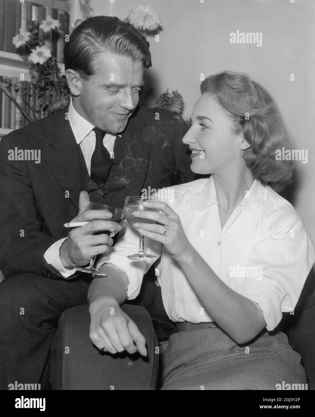 Chris Chataway , TV personality and former Olympic athlete , clinks glasses in a toast with his fiancée , Miss Anna Lett in London . 30th December 1958 Stock Photo