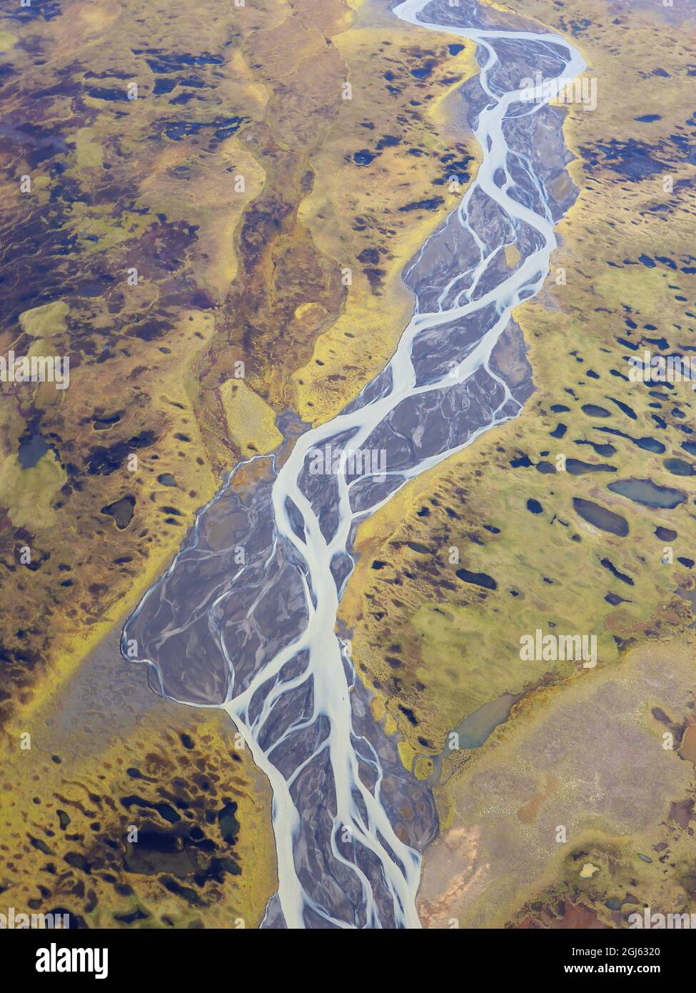Aerial photo of a braided river on a barren green and brown landscape. Stock Photo