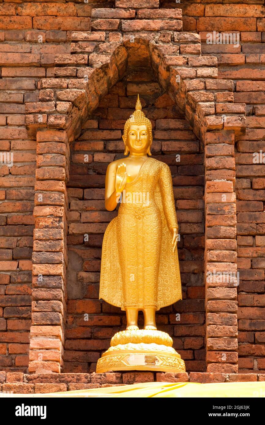 Thailand. Golden Buddha statue in a niche in a brick building. Stock Photo