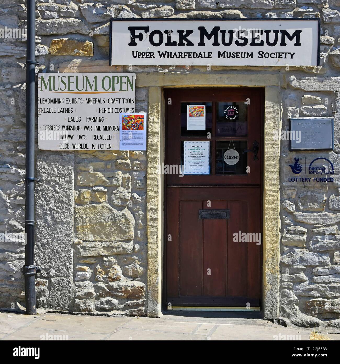 Close up stone wall & closed entrance door and signs at Upper Wharfdale Folk Museum Society in village of Grassington North Yorkshire England UK Stock Photo
