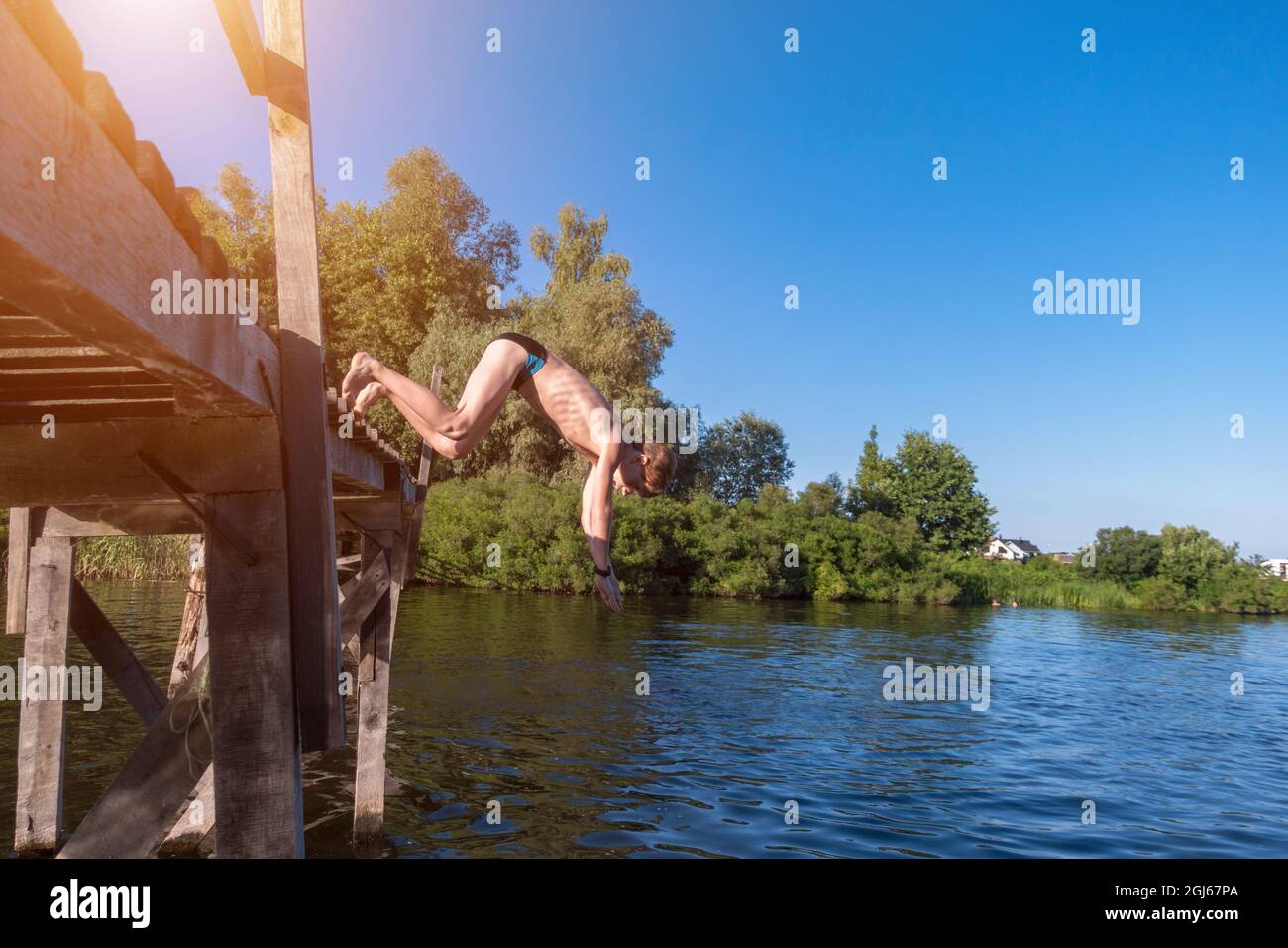 The boy jumps from a wooden bridge into the water Stock Photo - Alamy