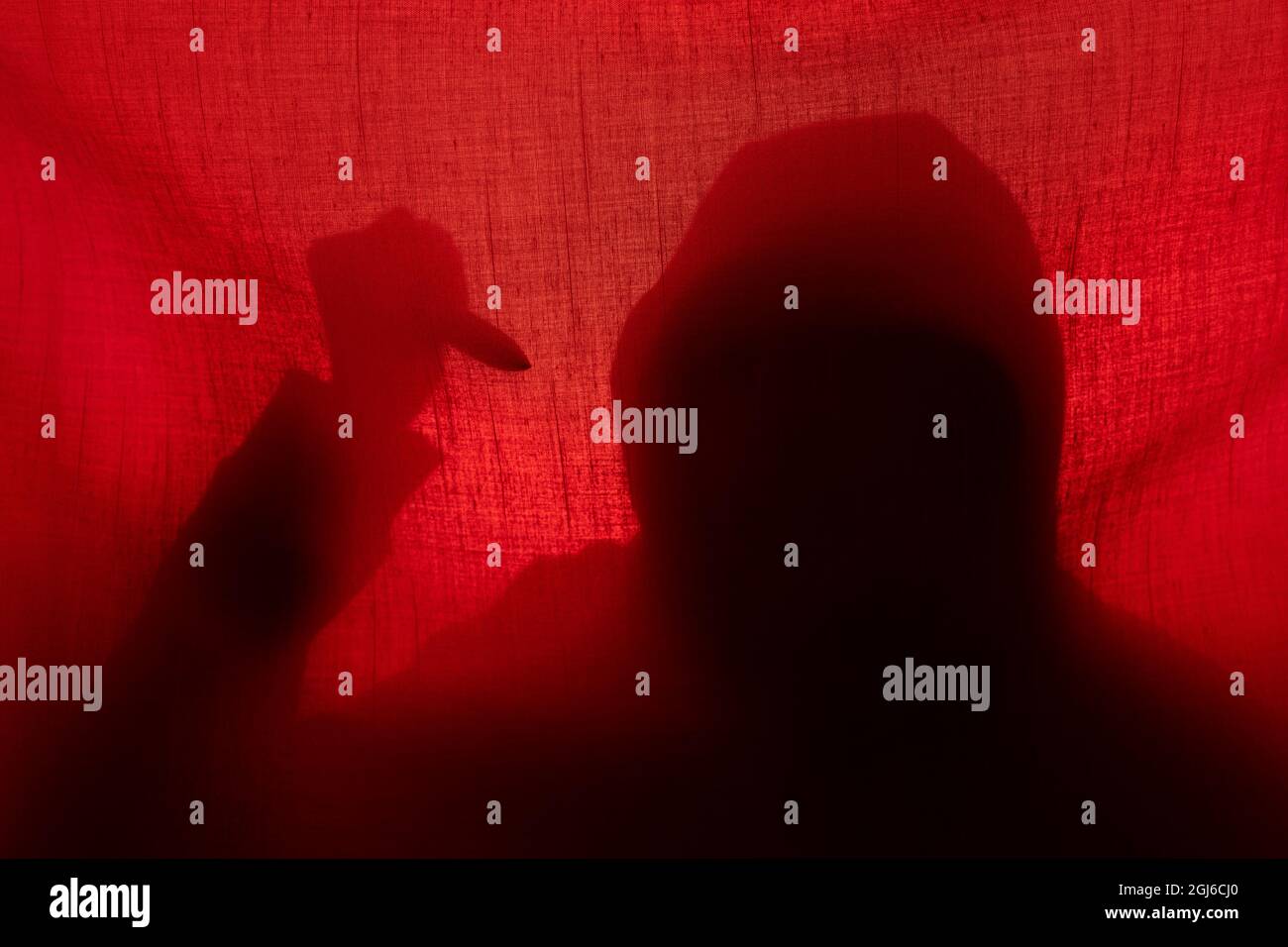 Man with a knife silhouette behind a curtain. Halloween and violence concept Stock Photo