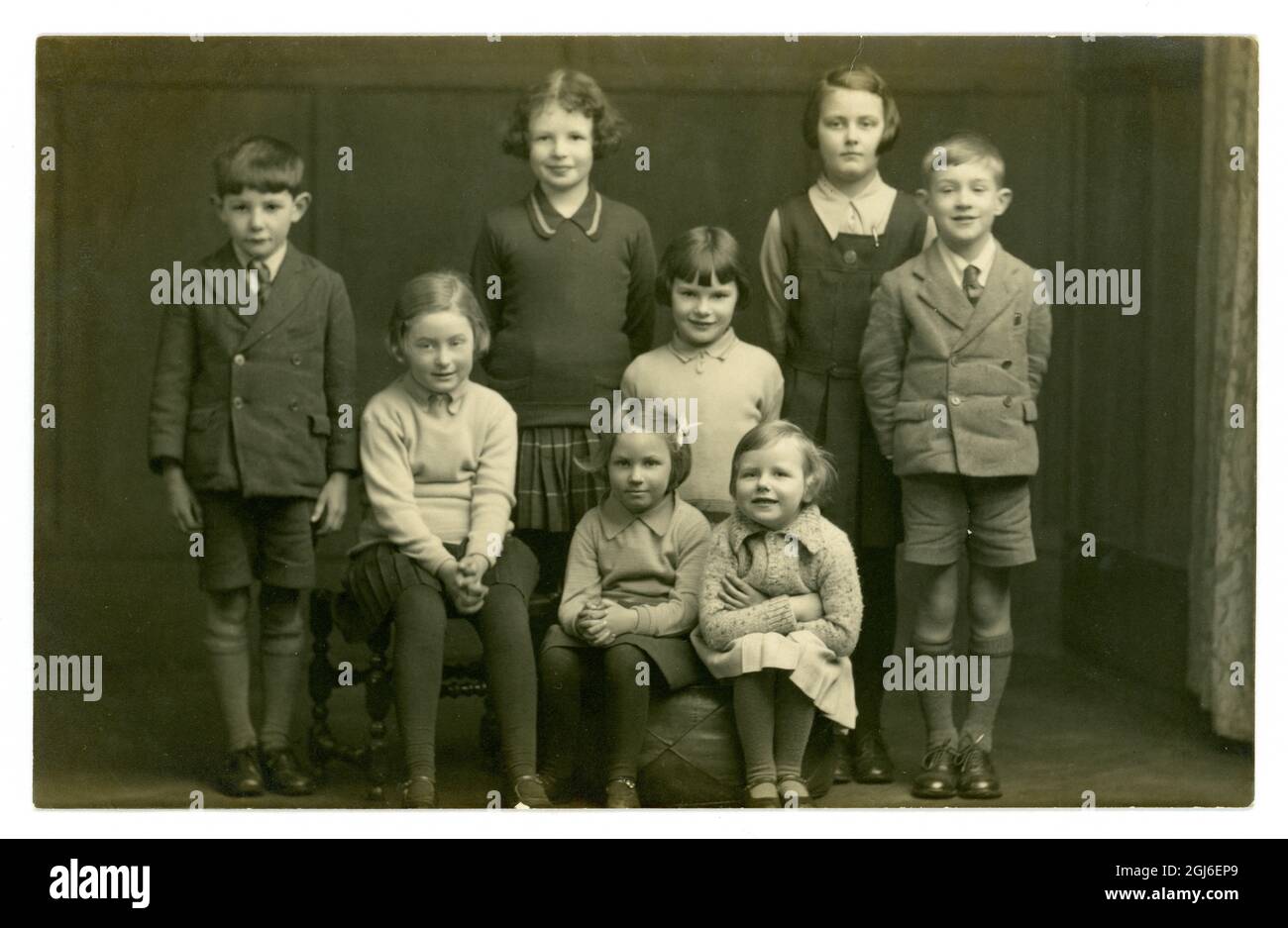 Original very clear image of 1930's era studio portrait postcard of 8 children, siblings or cousins, school uniforms, Lincoln, England, U.K. circa 1935 Stock Photo