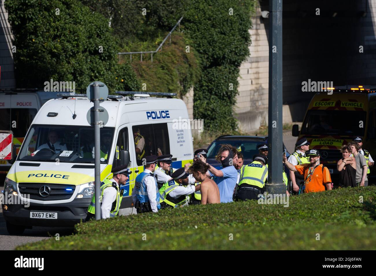 London, UK. 8th September, 2021. Metropolitan Police officers restrain  human rights activists trying to stop a convoy of trucks delivering  military equipment to ExCeL London for the DSEI 2021 arms fair. The