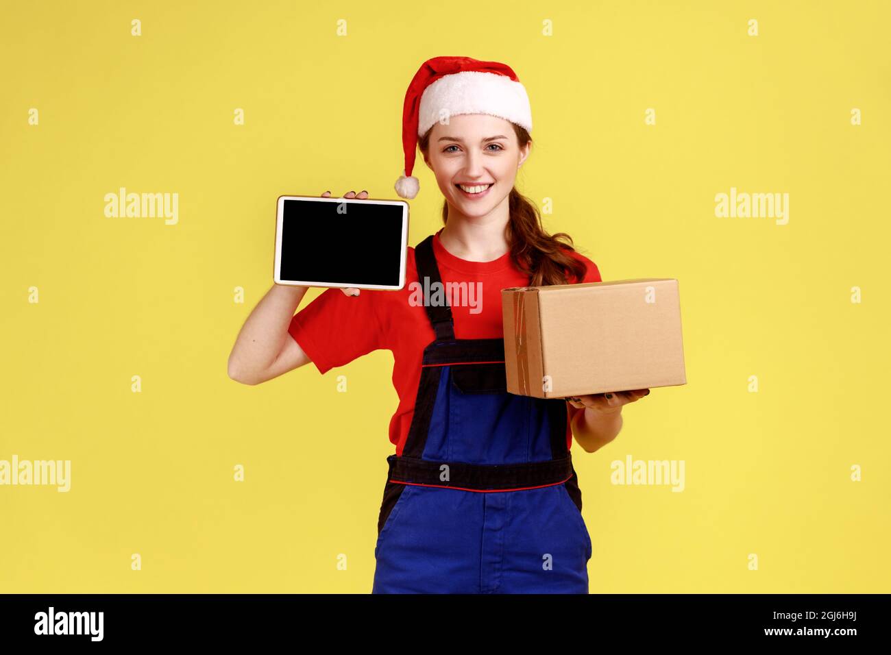 Courier woman in santa hat holding cardboard box and tablet with blank ...