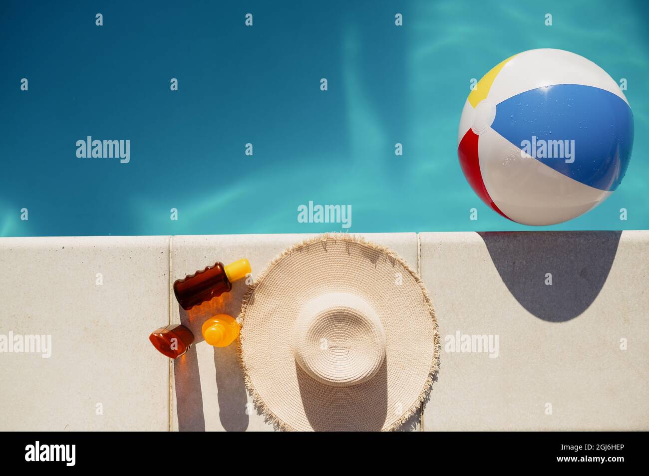 Suntan oil, hat and ball at the edge of the pool Stock Photo Alamy