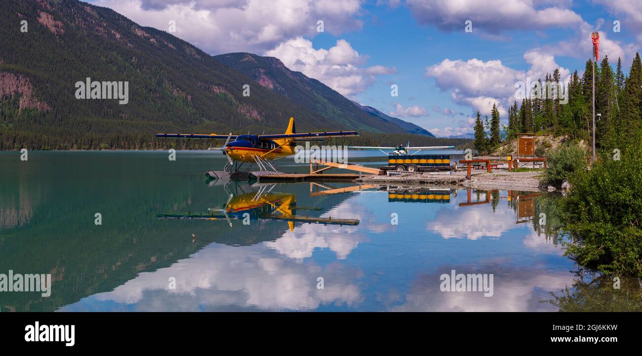 Canada, British Columbia. A brightly painted DE Havilland Otter sits at the dock on still Lake Muncho at the Rocky Mountain Lodge resort on the Alaska Stock Photo