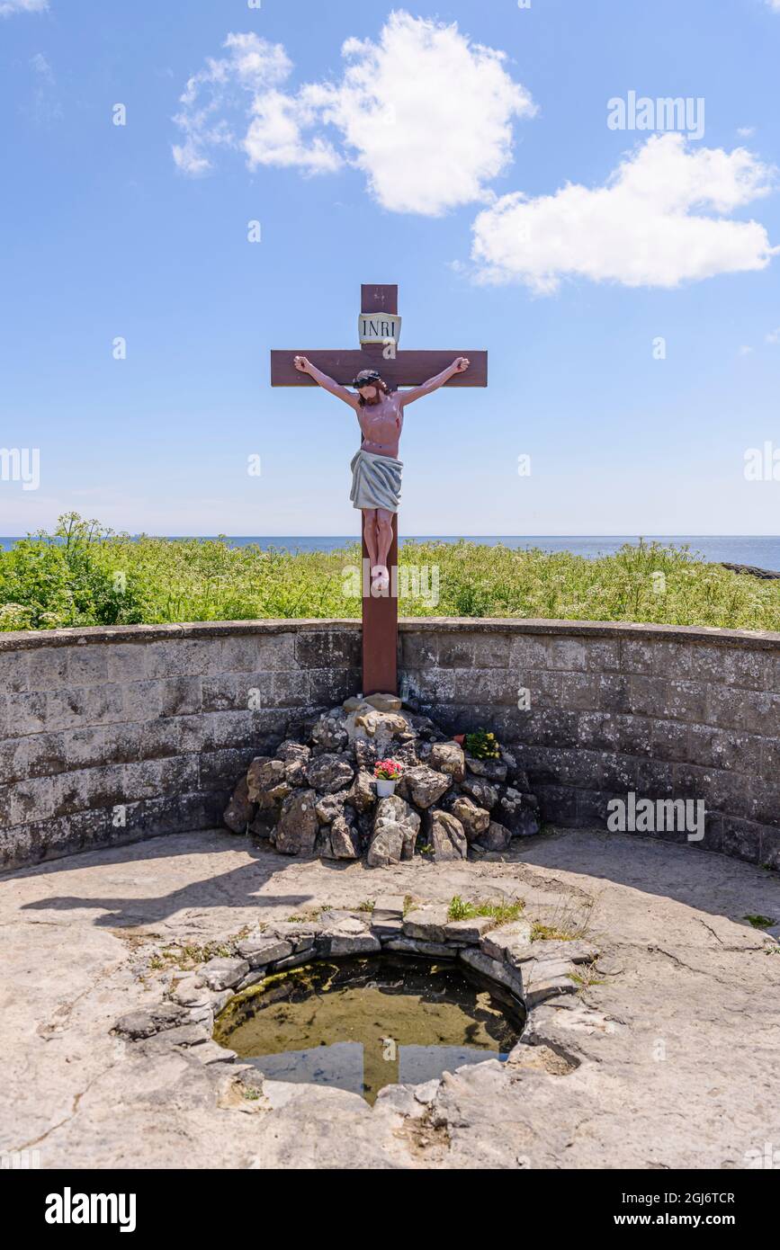 A traditional Irish holy well by the sea, with a large crucifix. Stock Photo