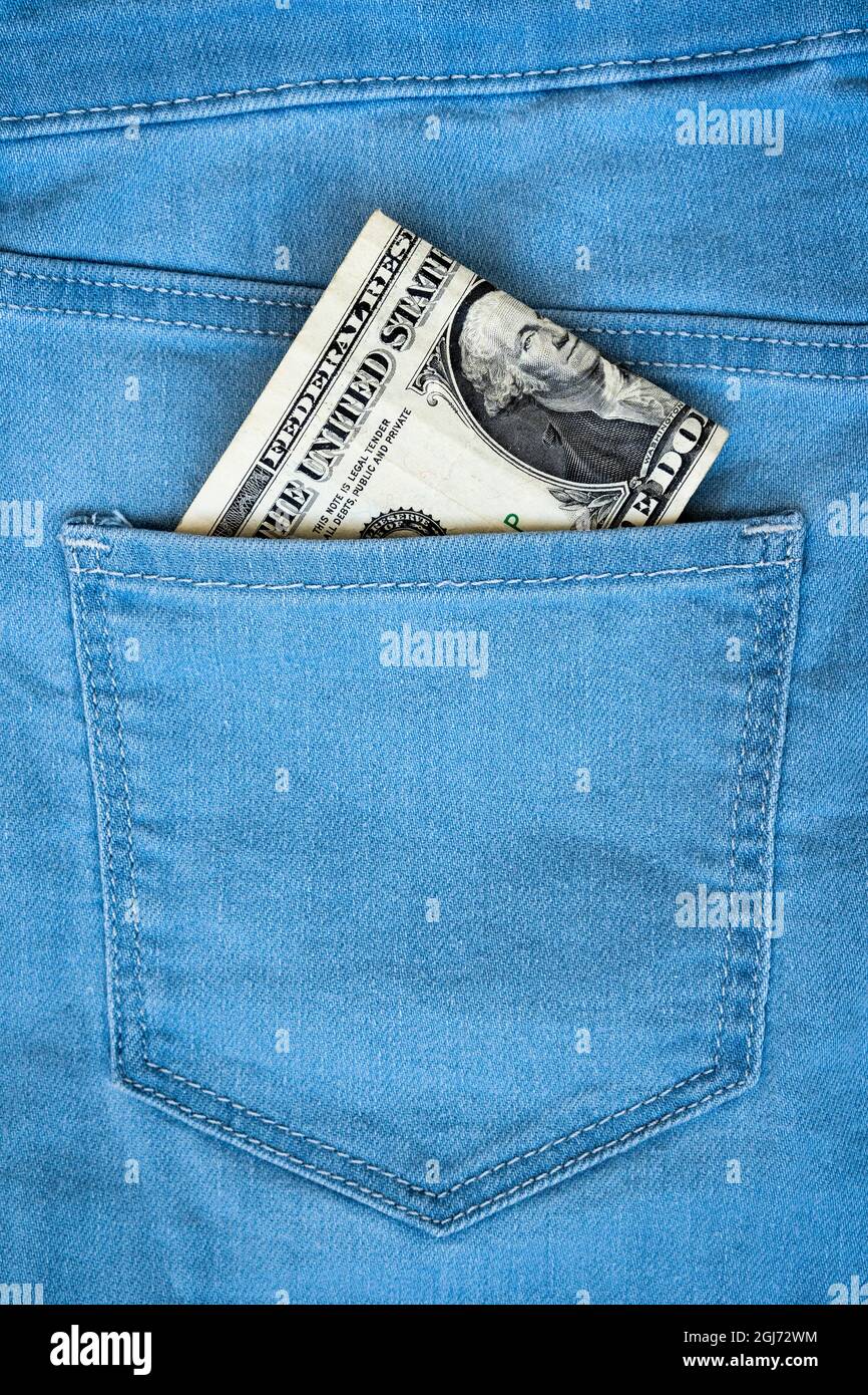 One dollar note in the back pocket of blue jeans. Dollar bill in jeans pocket close-up. Stock Photo