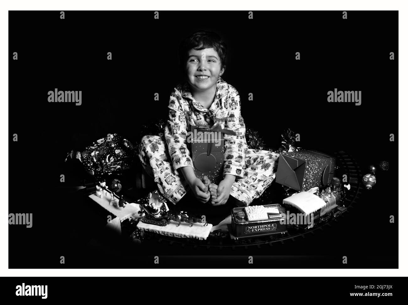 young happy boy in pyjamas with lots of Christmas presents Stock Photo