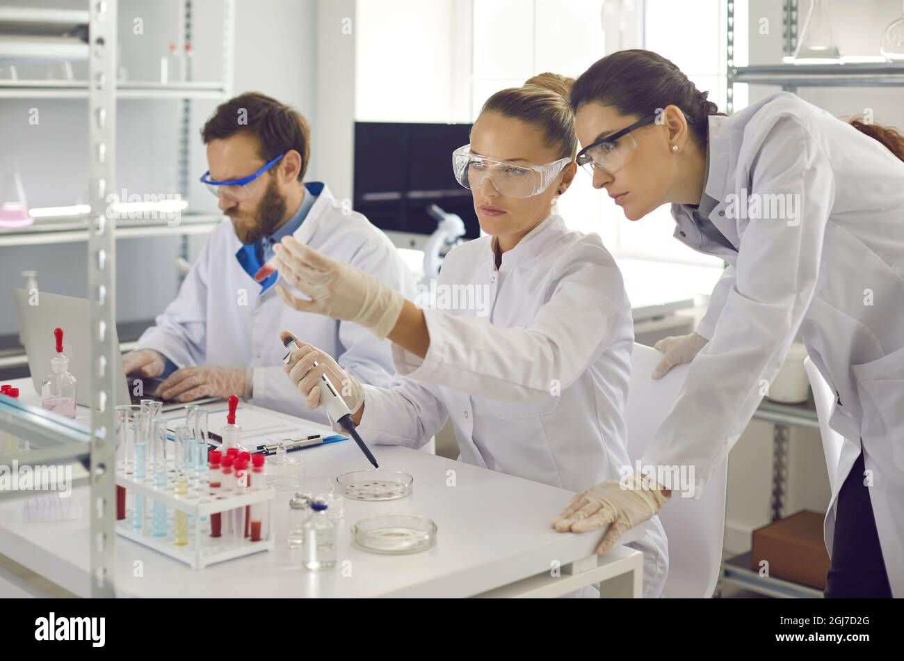 Group of scientist analyzing chemical liquids taking samples with pipette Stock Photo