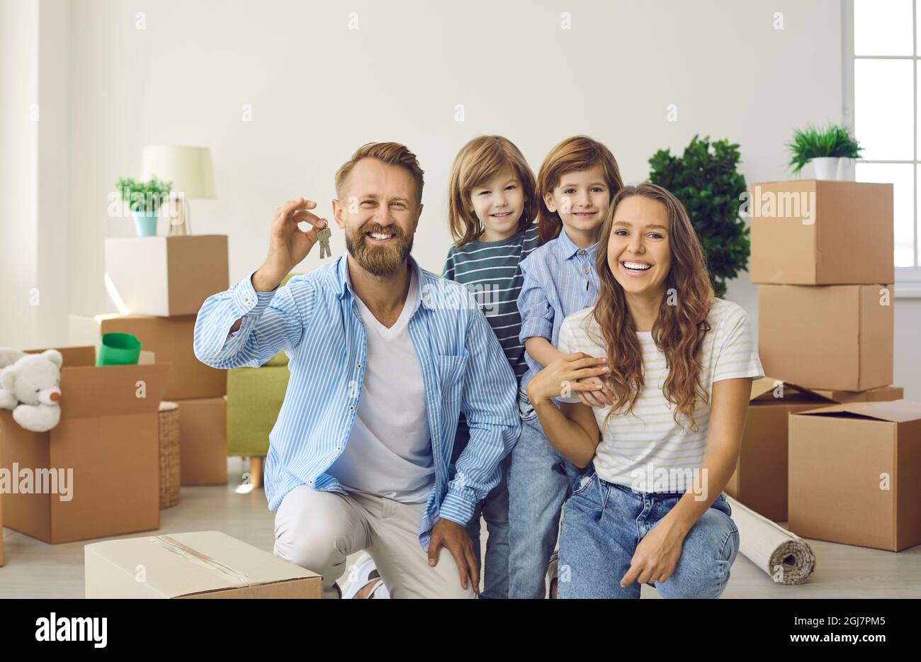 Smiling mother, father and children showing keys to their new house on ...