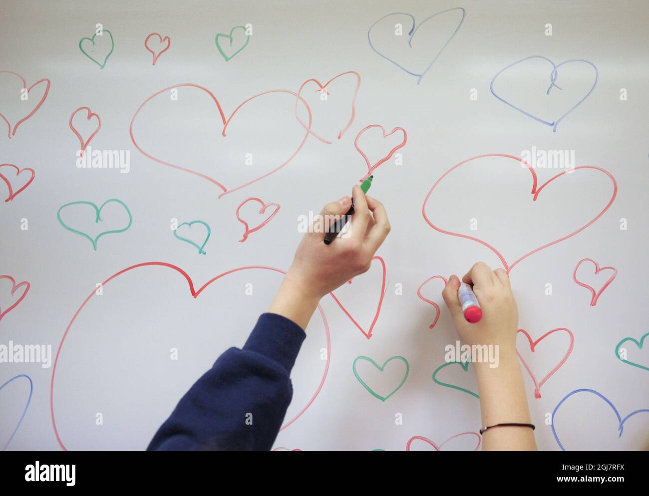 Children drawing hearts on whiteboard Stock Photo
