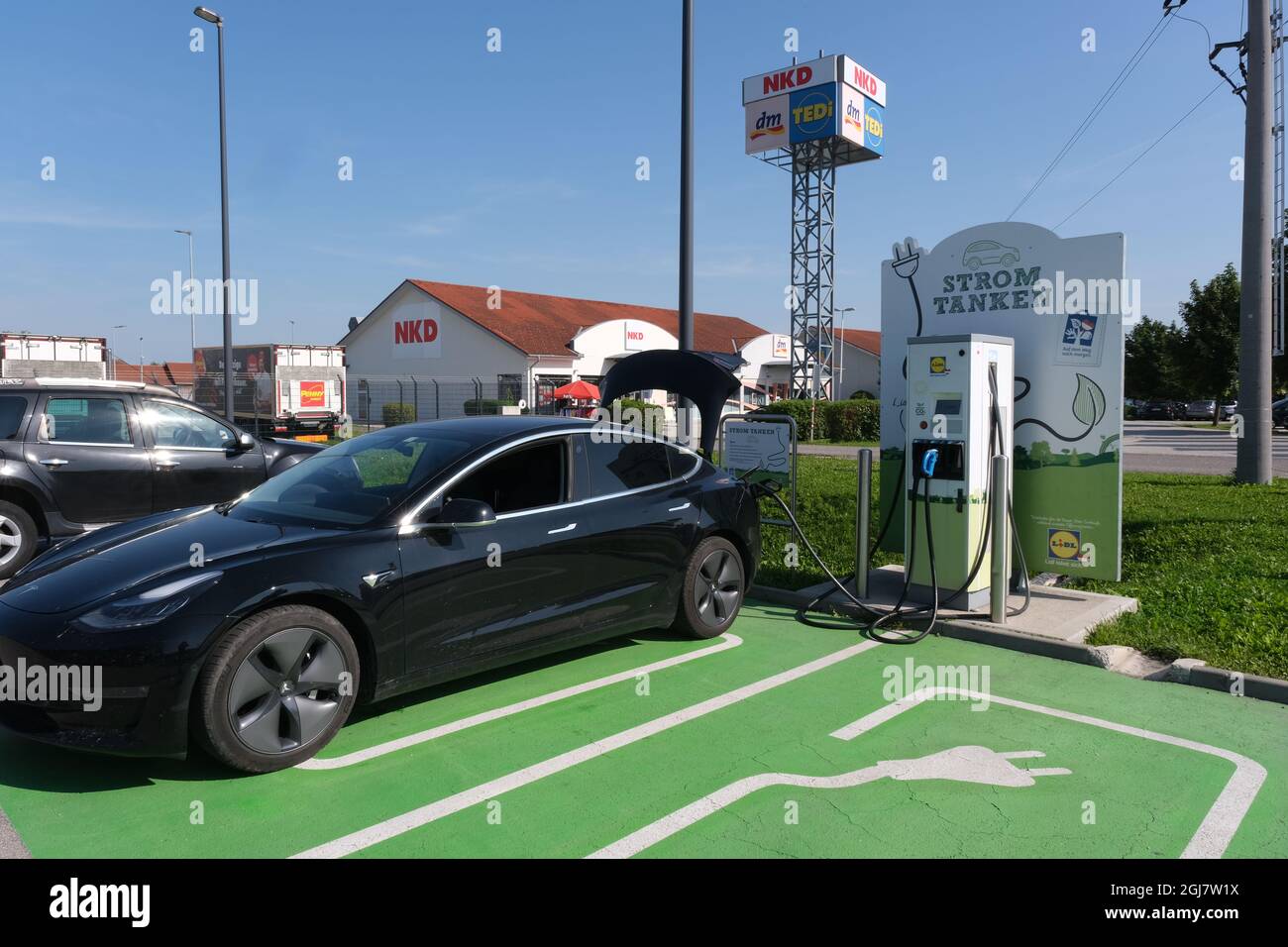 Ansfelden, Austria - August 12, 2021: A static shot of a solid black Tesla Model 3 dual motor long range charging at the LIDL supermarket DC charging Stock Photo