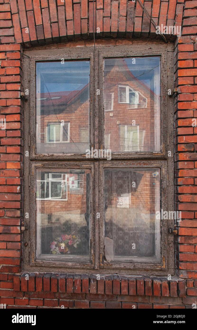 Window in a rowhouse in Wislica, Poland with reflections from the home across the street. Stock Photo