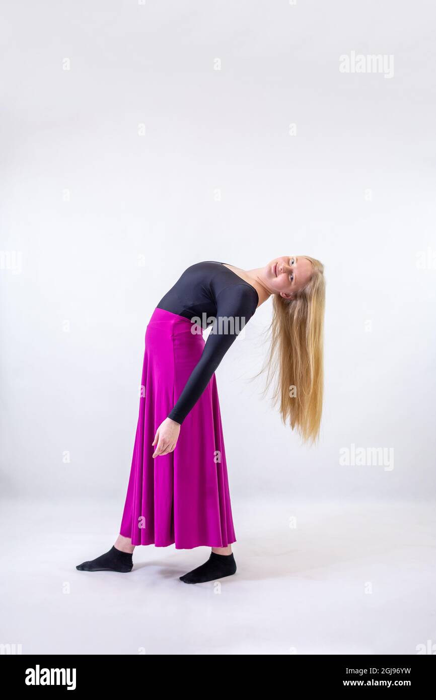 Young blonde blue-eyed dancer woman in long purple skirt on white background Stock Photo