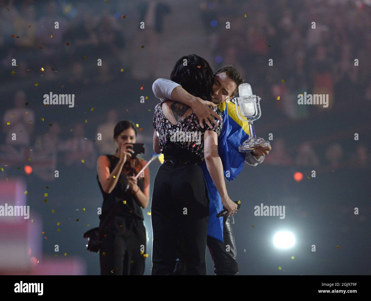 WIEN 20150523 The winner of the ESC 2014 Conchita Wurst congratulates and passes over the trophy to Mans Zelmerloew representing Sweden who celebrates winning the final of the Eurovision Song Contest 2015 in Vienna, Austria. Photo: Jessica Gow / TT / Kod 10070  Stock Photo