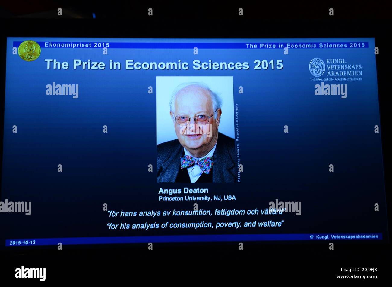 A picture of Professor Angus Deaton, winner of the 2015 Sveriges Riksbank Prize in Economic Sciences in Memory of Alfred Nobel is seen on a screen as the Permanent Secretary for the Royal Swedish Academy of Sciences addresses a press conference to announce the winner of the prize at the Royal Swedish Academy of Science, in Stockholm, Sweden, on Oct. 12, 2015. Photo: Maja Suslin / TT / code 10300  Stock Photo