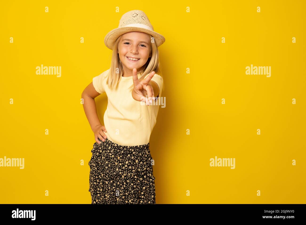Portrait of cute smiling little girl wearing straw hat with victory ...