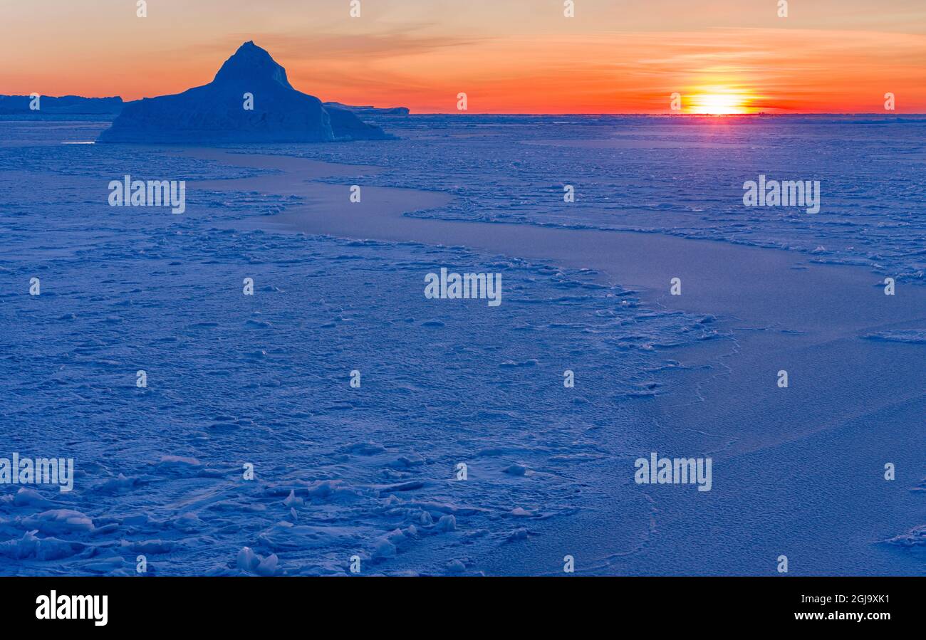 Sunset at the shore of frozen Disko Bay during winter, West Greenland ...