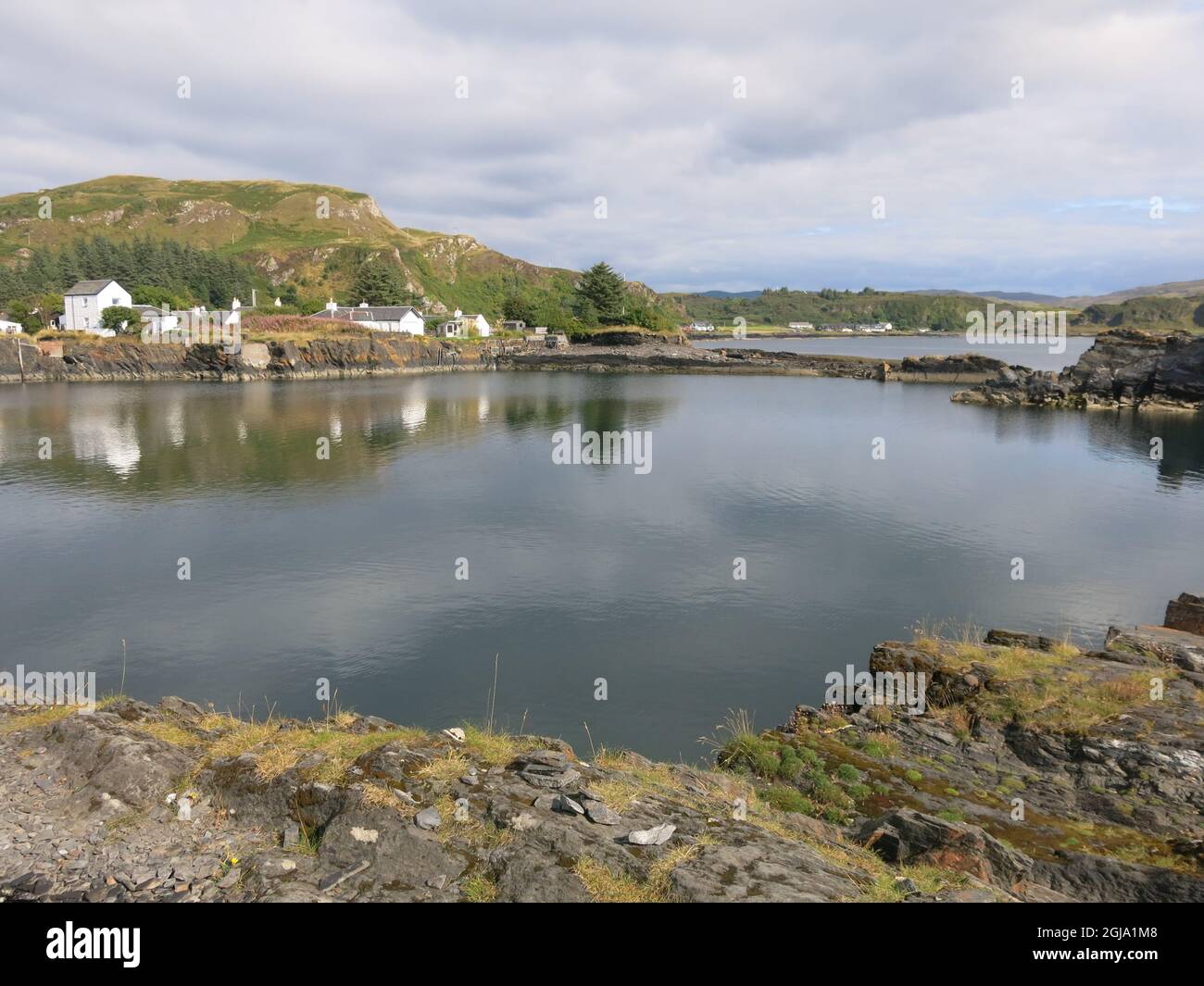Looking across from Easdale Island to the village of Ellenabeich on the Isle of Seil, one of the Slate Islands on Scotland's west coast. Stock Photo