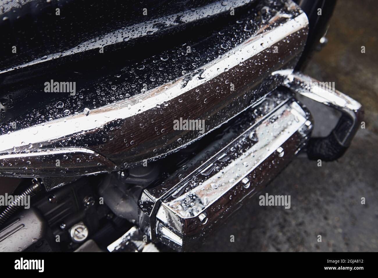 Black motorcycle after rain. Water drops on bike. Chrome engine closeup. Stock Photo