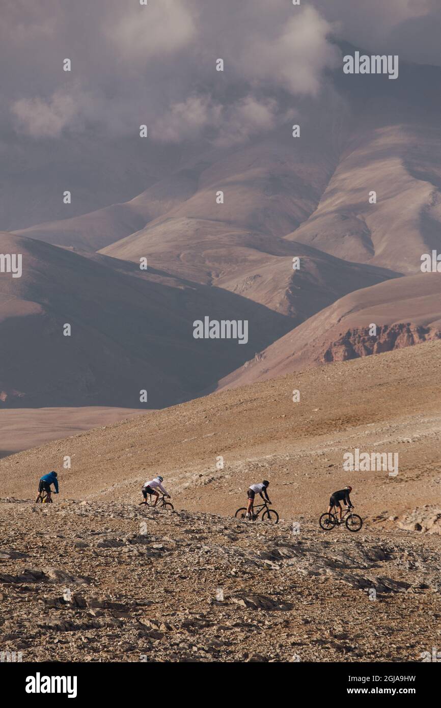 Vertical shot of cyclers on a mountain with cloudy skies in the background Stock Photo