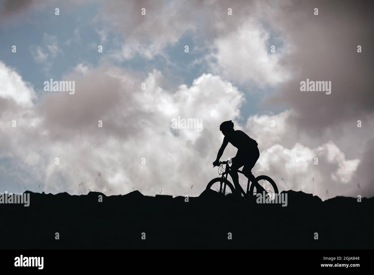 Beautiful shot of a cycler's silhouette in front of the cloudy skie Stock Photo