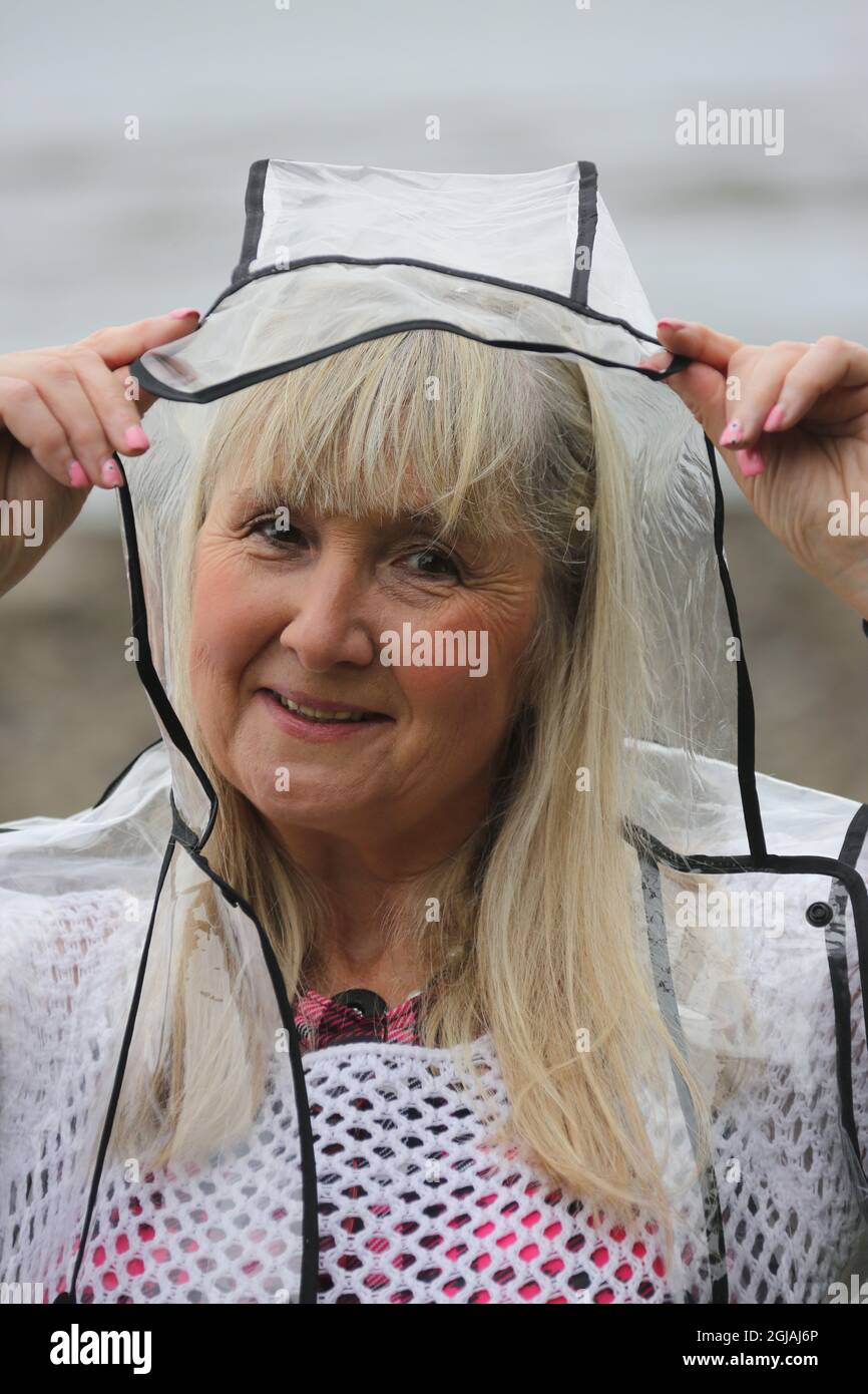 White caucasian woman aged 64 wears a clear plastic raincoat Stock Photo