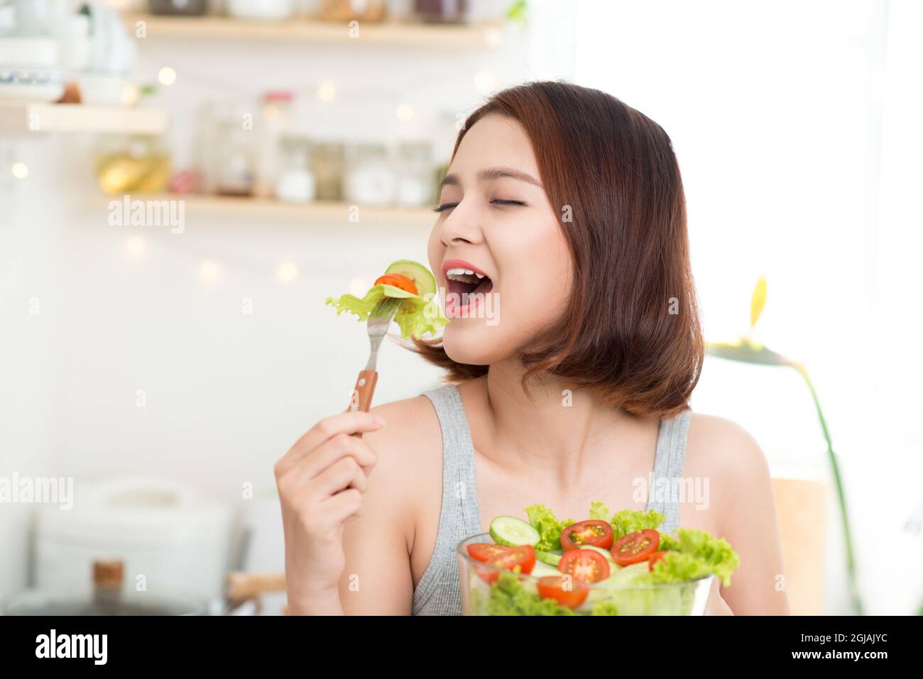 Beautiful young asian girl eating salad. smiling happy girl eating healthy food. Stock Photo