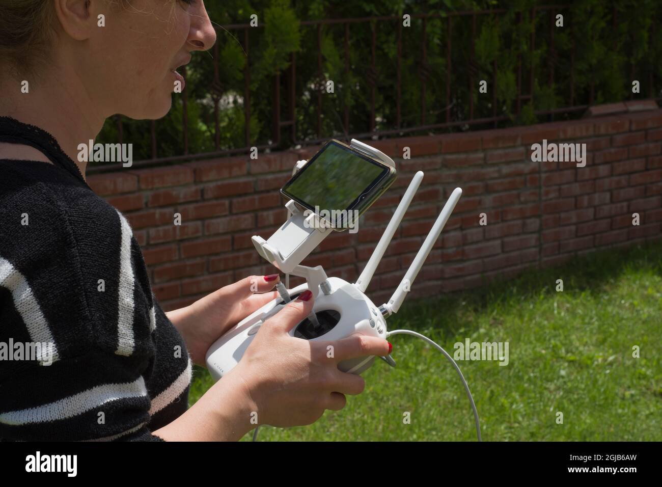 young woman flying drone in the garden of their house. Selective Focus remote control. Stock Photo