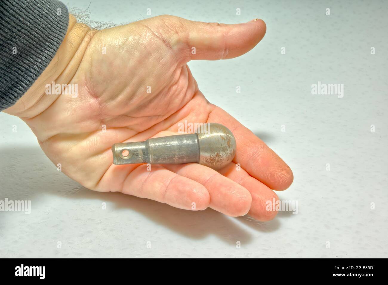 An unfinished automotive ball joint being held in a human hand. This common car part is mostly used for steering systems and front wheel drive axles. Stock Photo