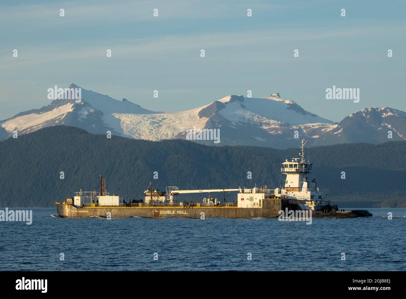 USA, Alaska, Juneau, DoubleHulled fuel barge motors past glacier