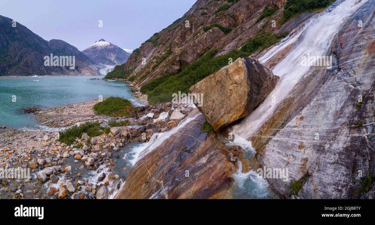 USA, Alaska, Tracy Arm-Fords Terror Wilderness, Waterfall flowing down cliff side along Endicott Arm near Dawes Glacier at dusk on summer evening Stock Photo