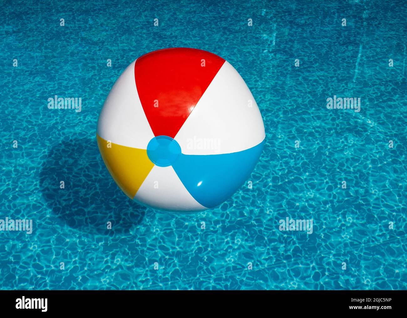 Inflatable beach ball floating in swimming pool Stock Photo