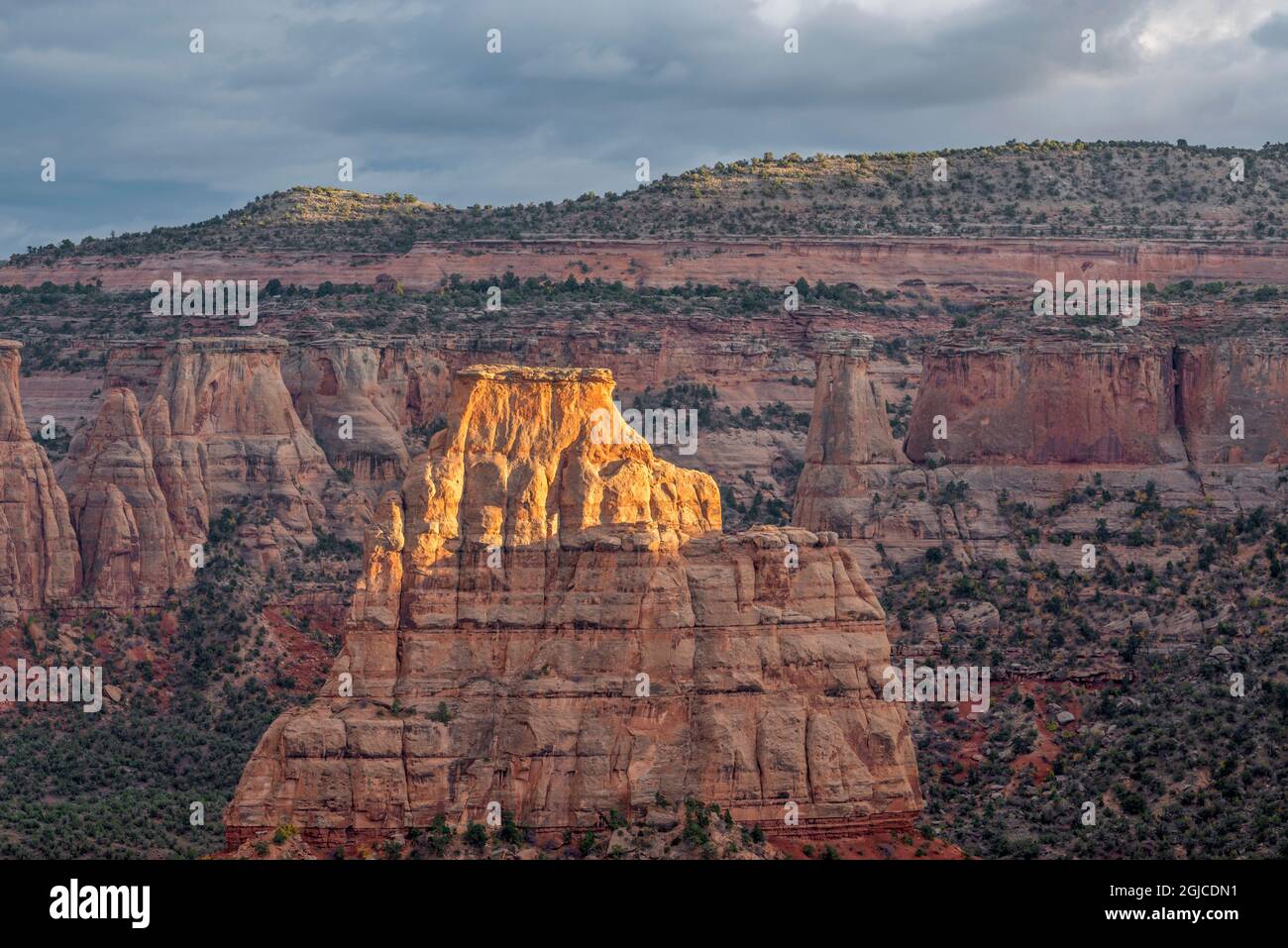 USA, Colorado, Colorado National Monument, Shaft of light brightens top of Independence Monument; view southeast across Wedding Canyon from Book Cliff Stock Photo