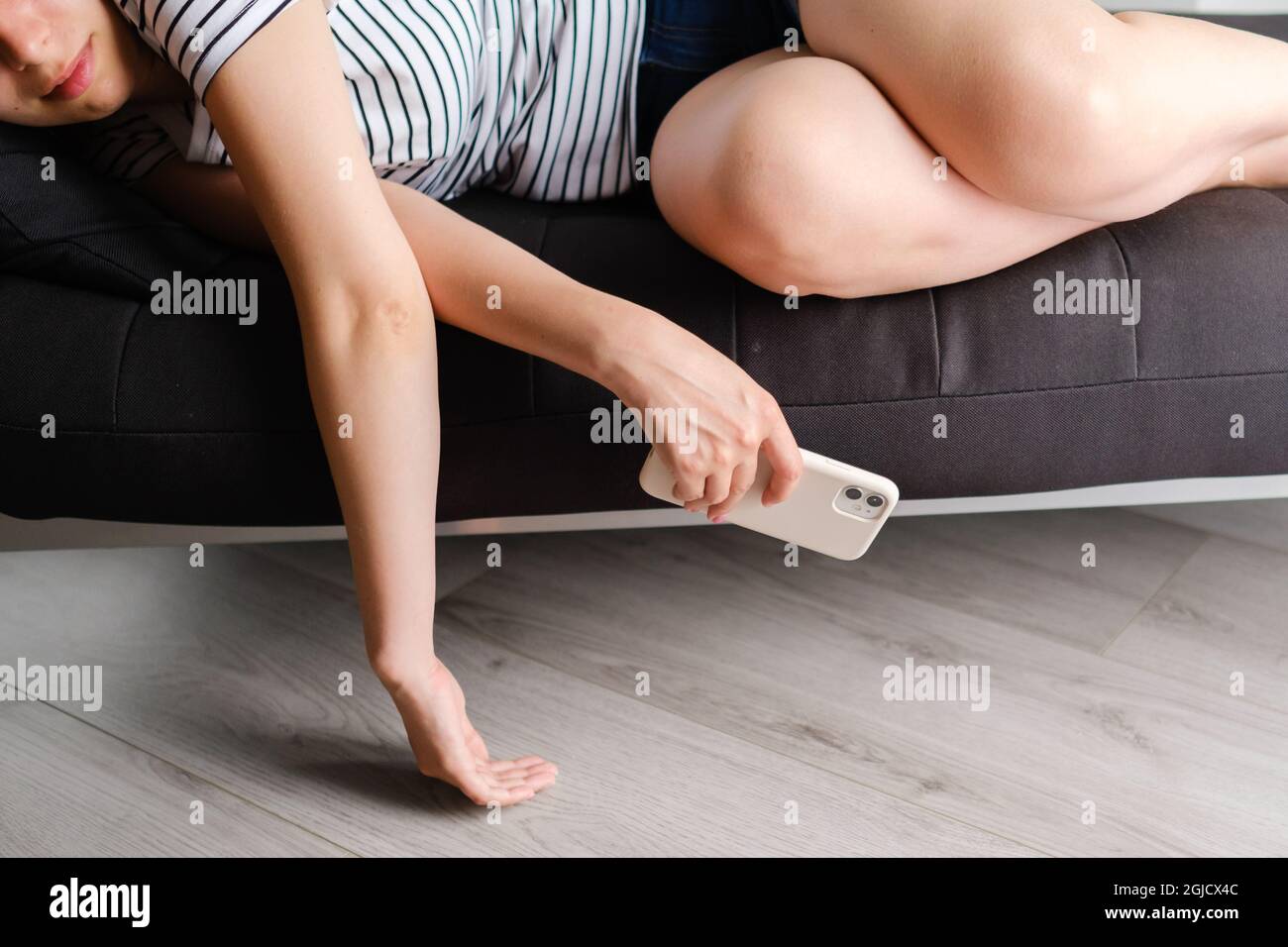 Young woman fall asleep after long using of smart phone on the sofa in the living room. Bad influence of social web sites Stock Photo