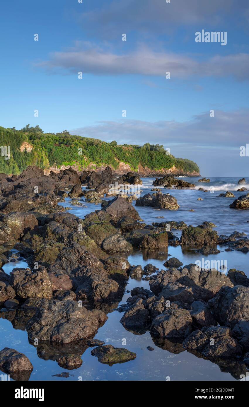 USA, Hawaii, Big Island of Hawaii. Laupahoehoe Point Beach Park, Sunrise on volcanic rock, incoming waves and distant forest. Stock Photo