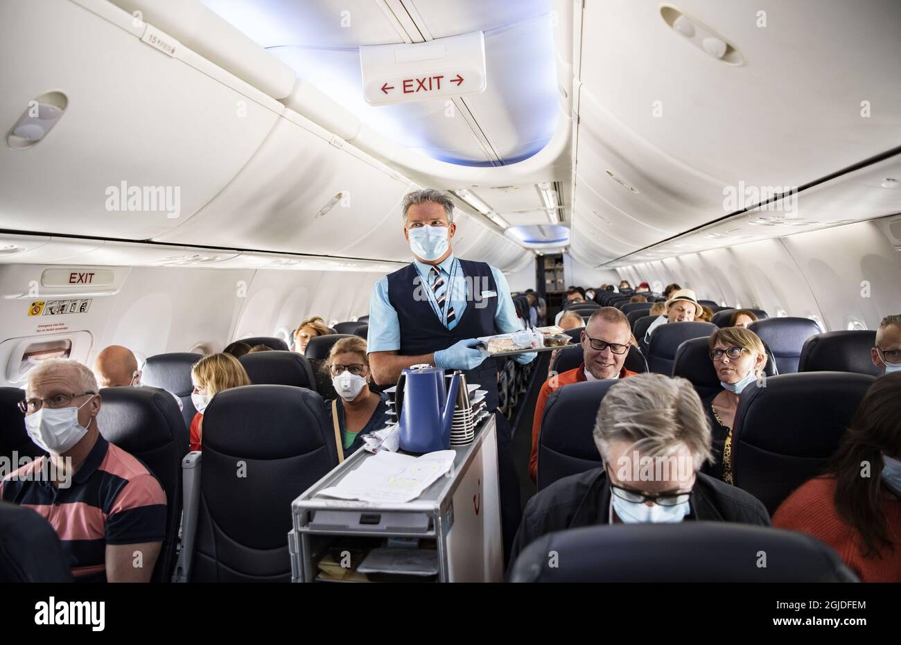 Flight attendant wearing face masks and plastic gloves serving food during the first chartered