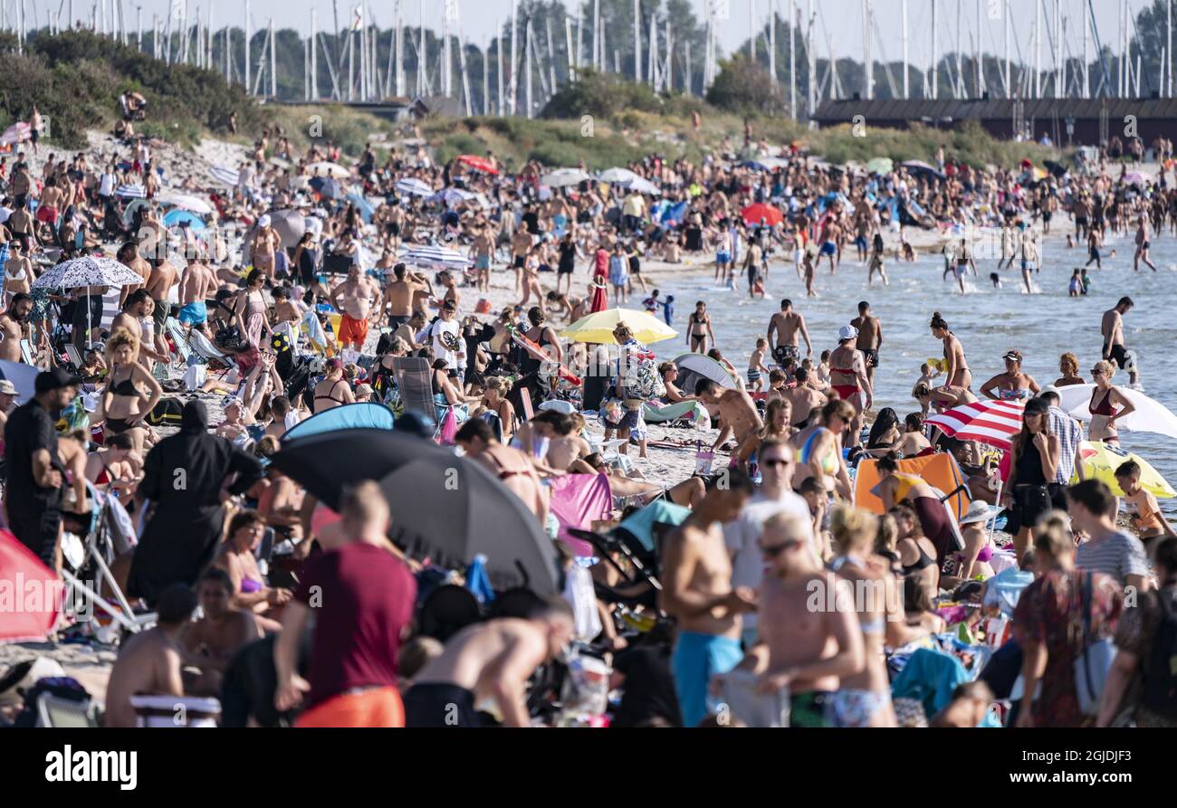 People Enjoying The Sun And Warm Weather On A Crowded Beach In Lomma 