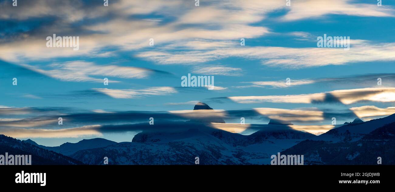 crepuscular Shadows cast by Teton Peaks before Sunrise. Altocumulus lenticularis clouds are also visible. Stock Photo