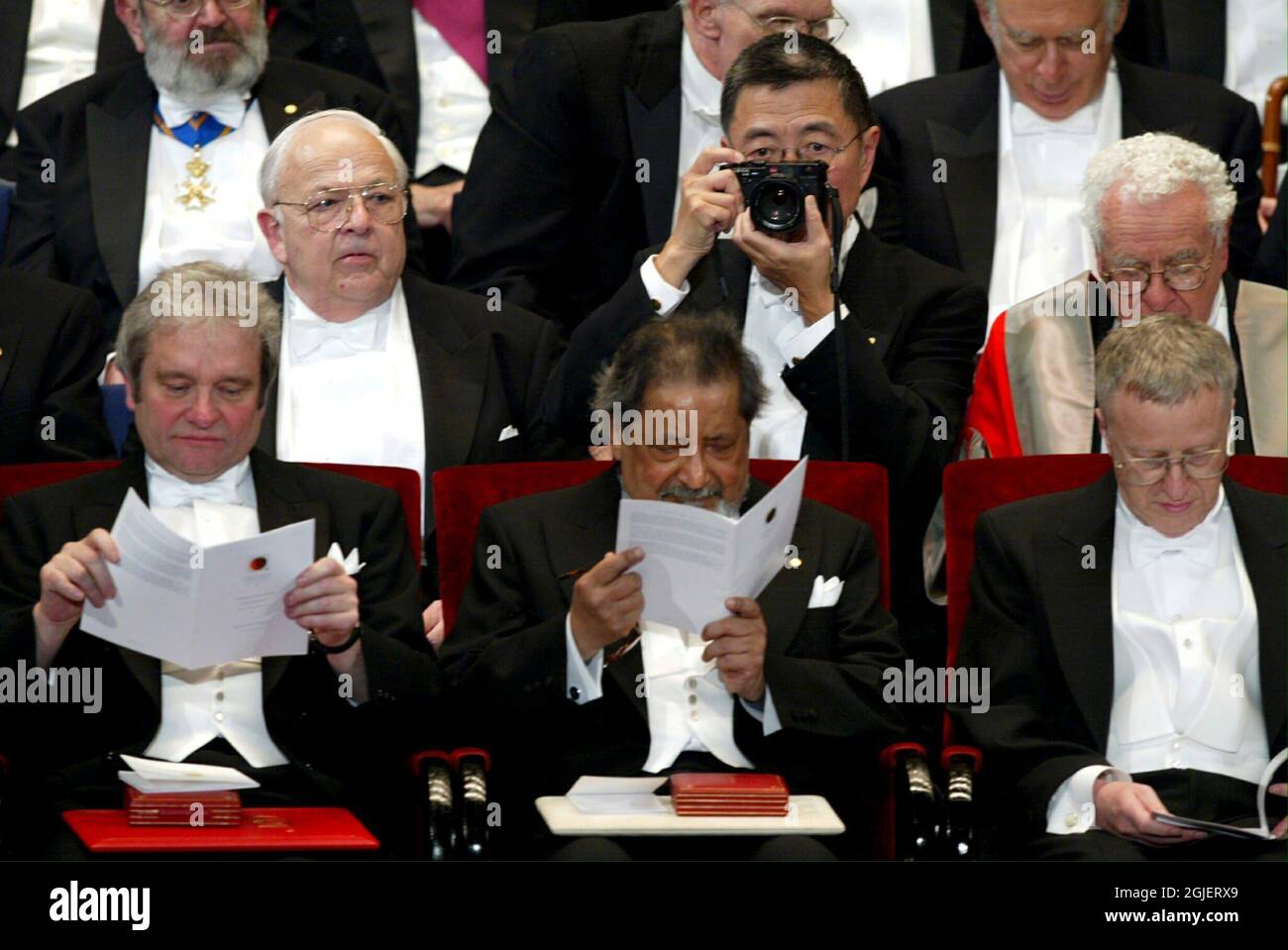 The Japanese 1976 Noble Prize winner for physics, Samuel Chao Chung Ting (2ND ROW, C), takes a photo of the audience during the centennial 2001 Nobel ceremony at the Concert Hall in Stockholm. In the first row are this years winners (L-R) British physics laureate Paul Nurse, British Literature laureate Sir V.S. Naipaul and American Economics laureate George A. Akerlof. Stock Photo