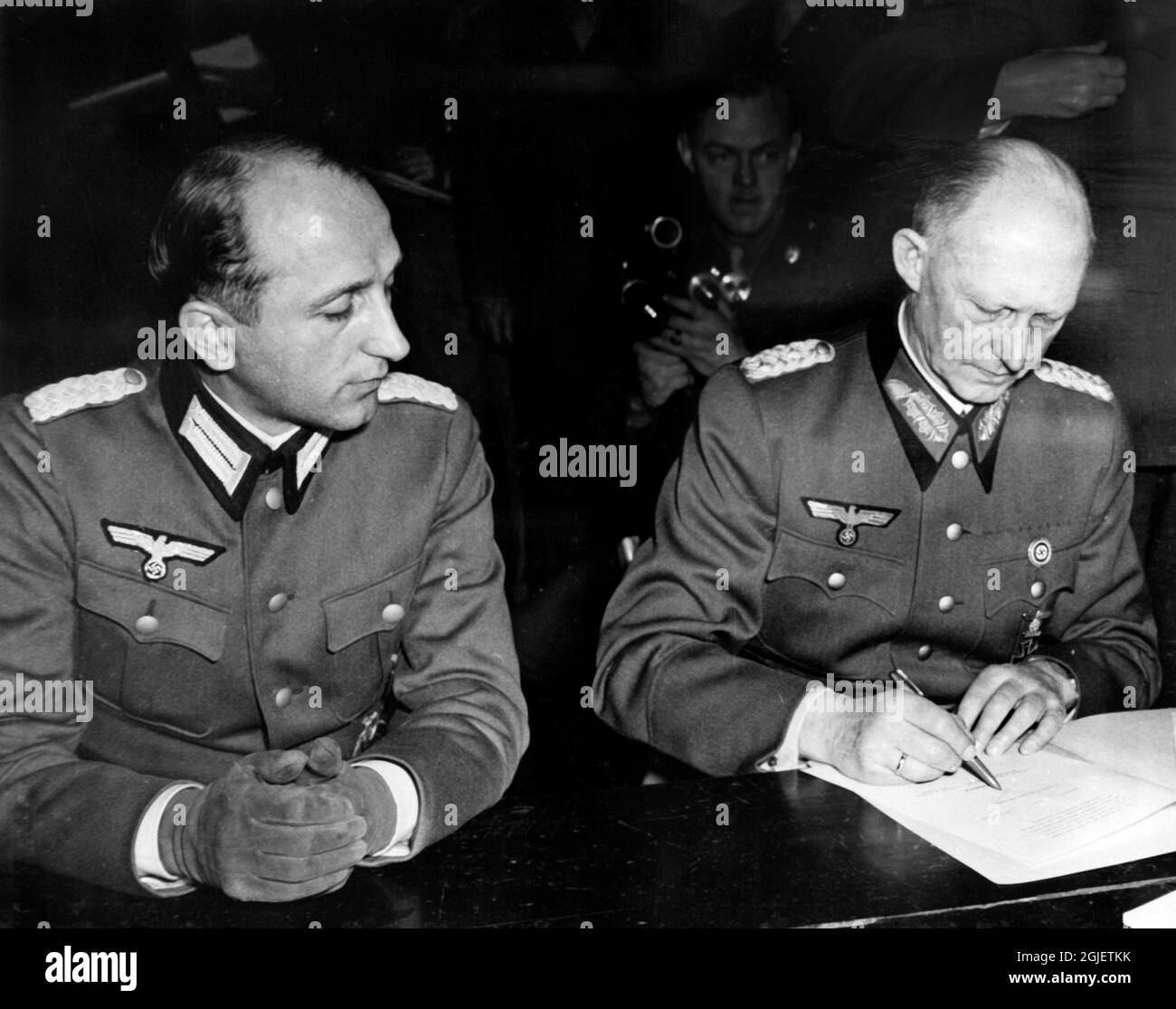 On behalf of the German High Command, Colonel General Alfred Jodl signs the Act of Military Surrender requiring German forces to cease operations on May 8, 1945.  On General Jodl's right is Major Wilhelm Oxenius of the German general staff Stock Photo