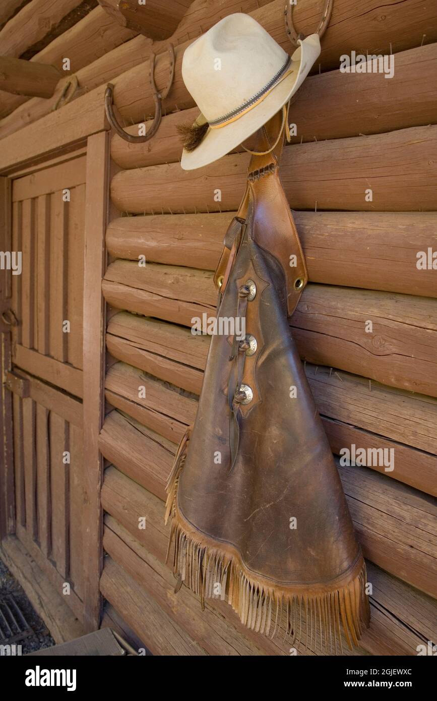 USA, Montana, Livingston, cowboy hat and chaps hanging on barn wall. Stock Photo