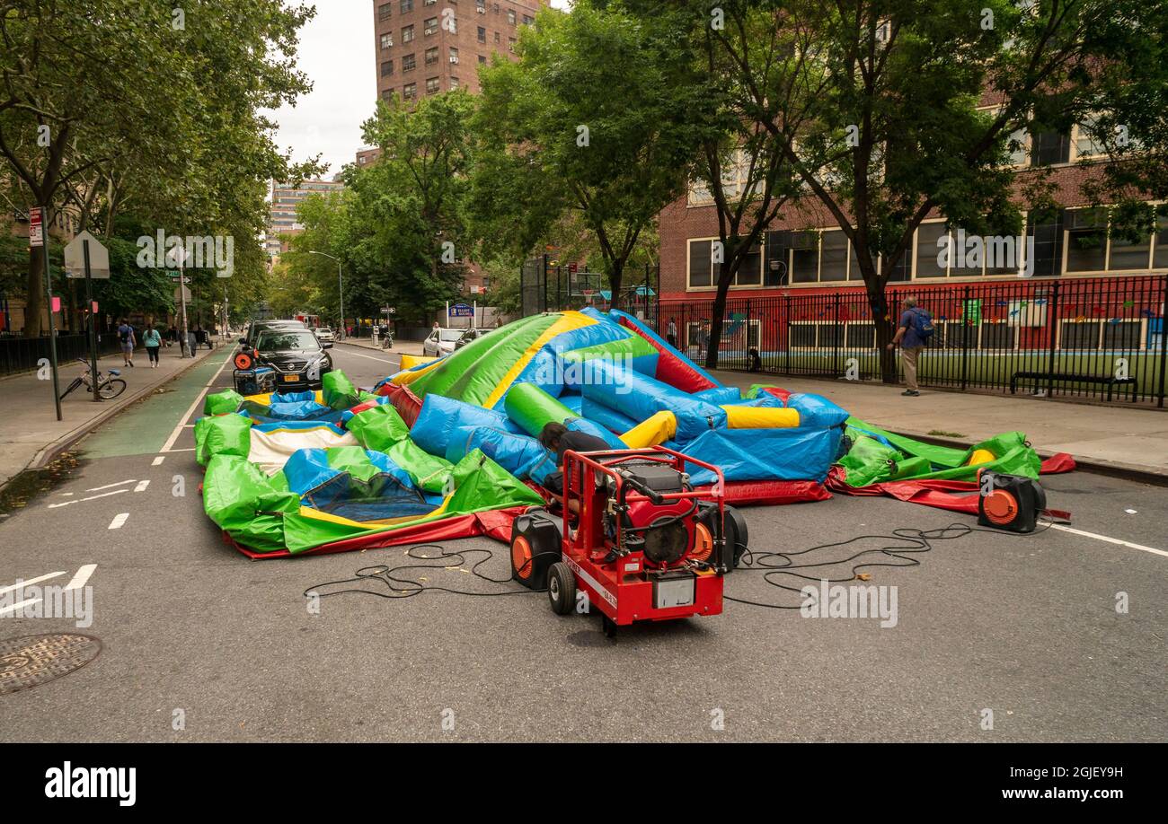 A worker deflates a “bouncy castle” inflatable in the Chelsea neighborhood of New York at the end of a street fair on Saturday, August 28, 2021. (© Richard B. Levine) Stock Photo