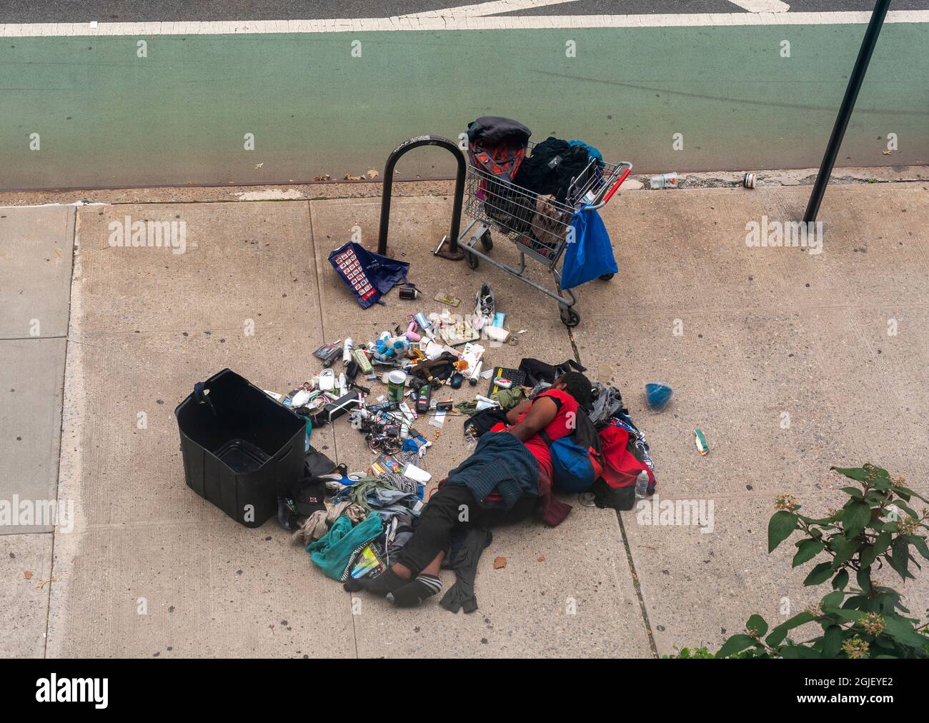Homeless individual sleeps in the middle of the sidewalk in Chelsea in New York with his possessions strewn about, seen on Sunday, August 29, 2021. (© Richard B. Levine) Stock Photo