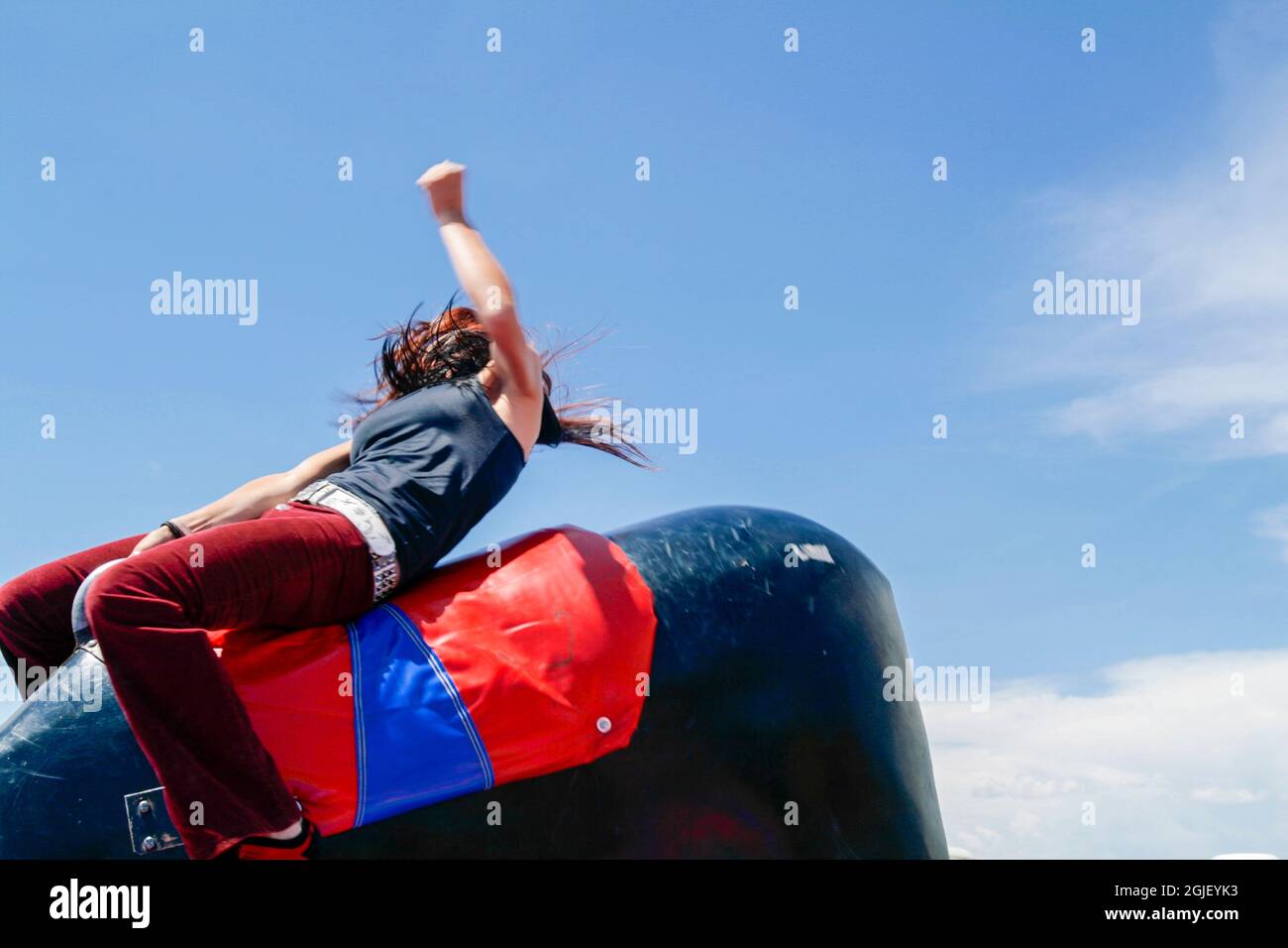 Galisteo, New Mexico, USA. Girl rides mechanical bull at rodeo. Stock Photo