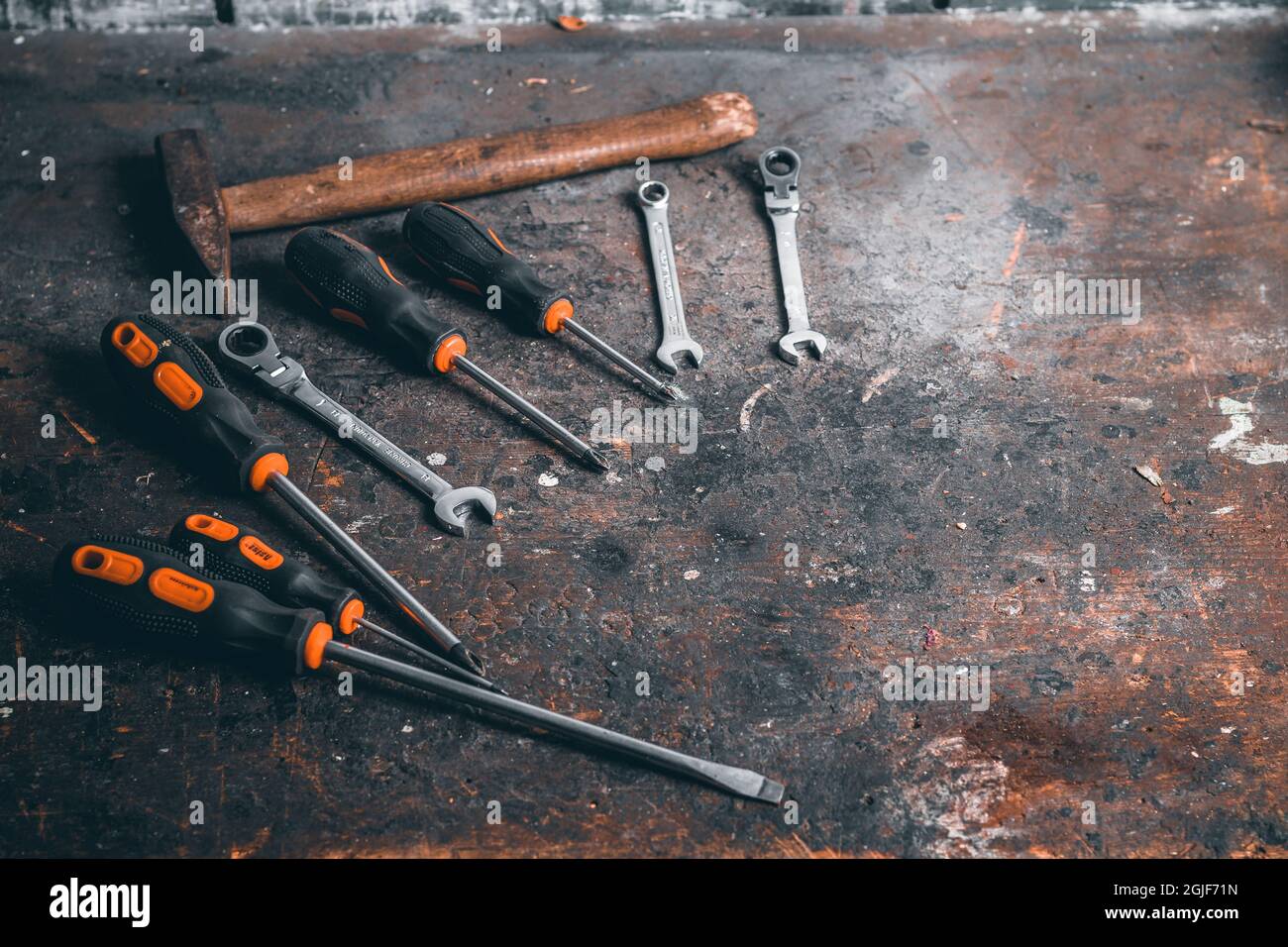 Screwdrivers, wrenches and hammer on a wooden workbench. Top view on working tools with space for text. Construction tools on work wooden table. Stock Photo